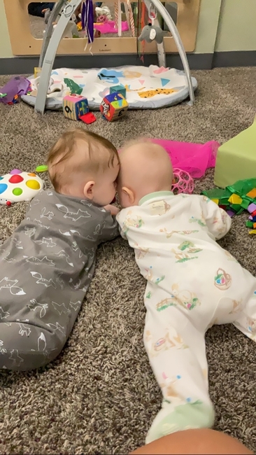 Two babies playing together on the floor