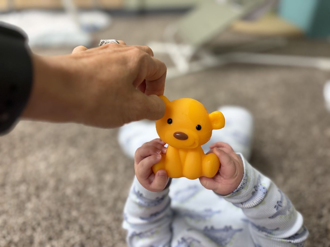 A baby's hands holding a small teddy bear