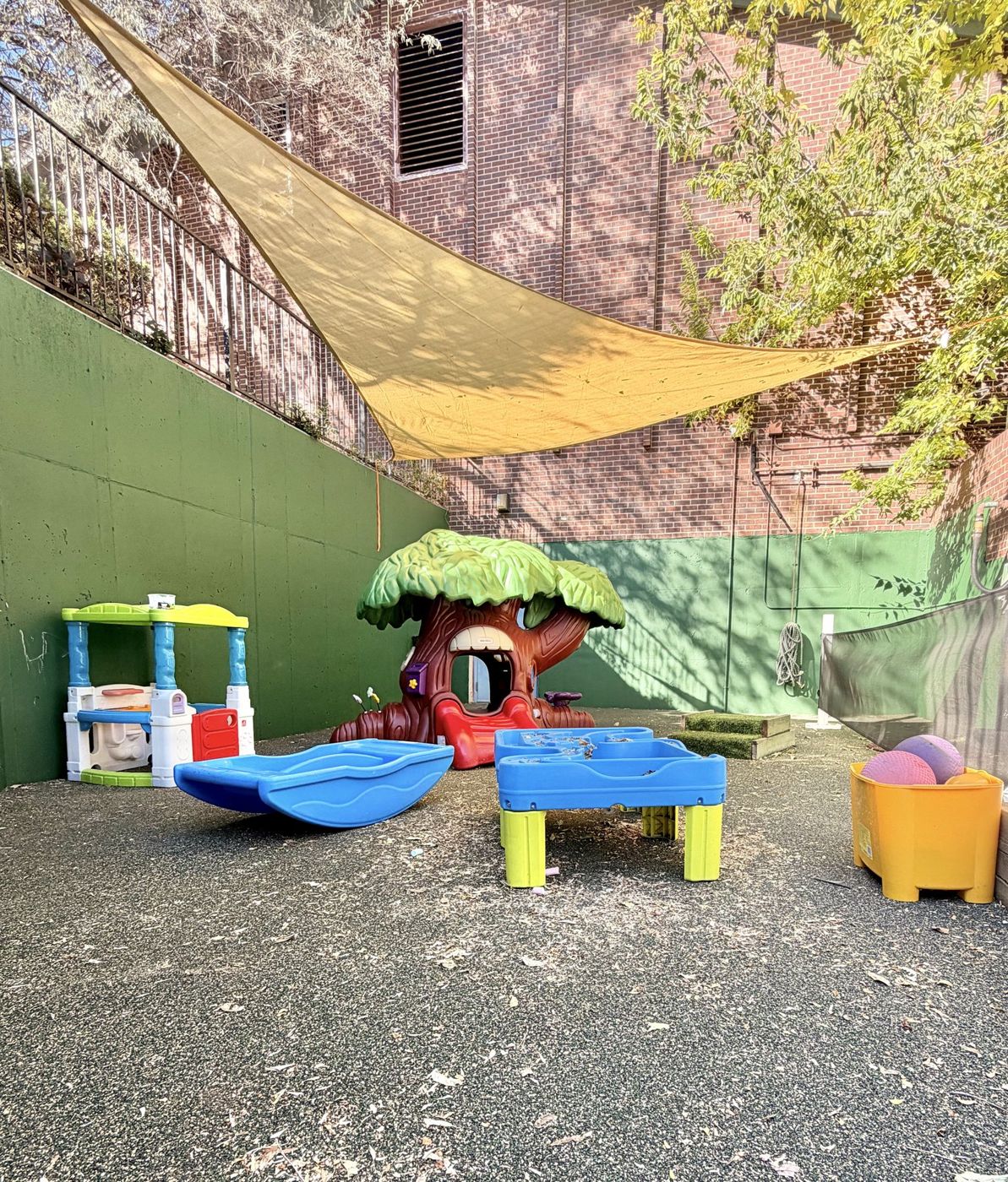A shaded play area with a water table and climbers