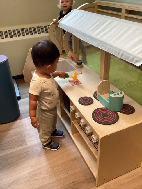 A toddler playing in the classroom kitchen