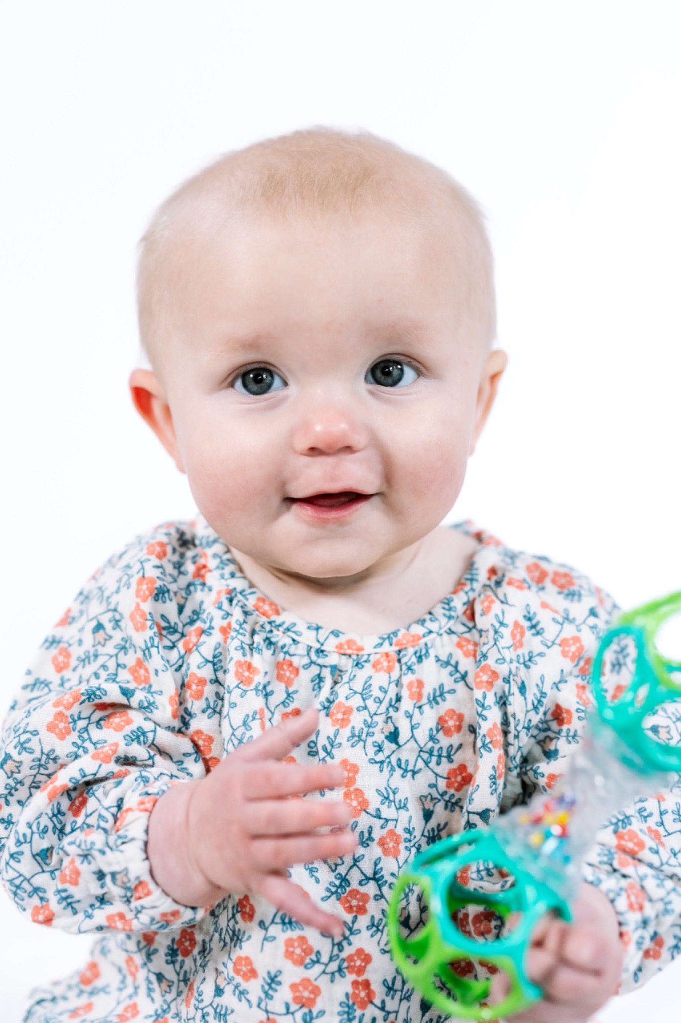 A smiling baby holding a colorful toy